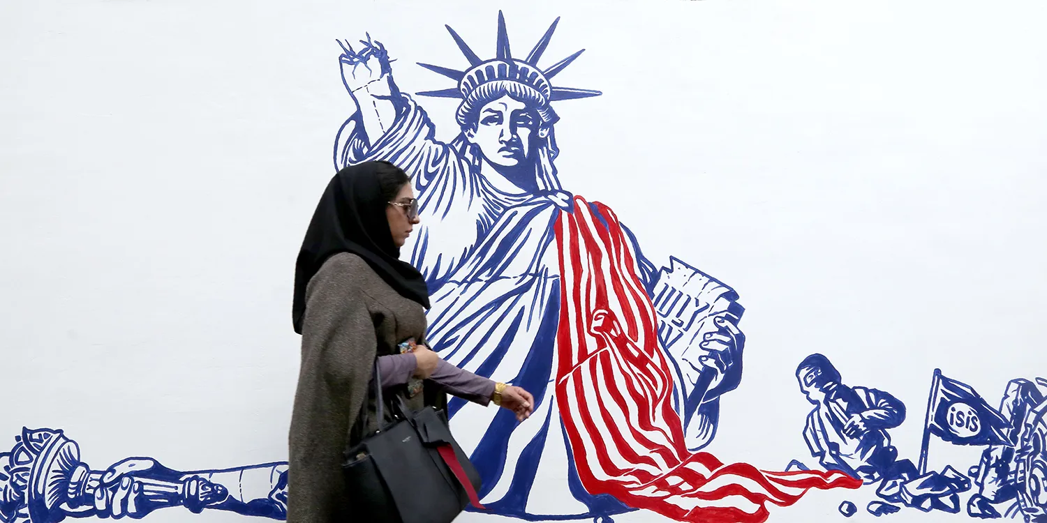 A woman in a hijab walks past an anti-American mural in Tehran depicting the Statue of Liberty